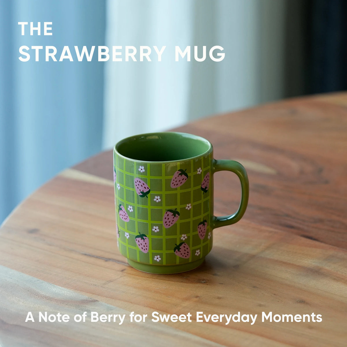 Green mug with strawberry pattern on a wooden table