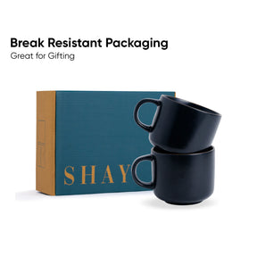 Two black mugs stacked in front of a teal box with 'SHAY' branding, on a white background.