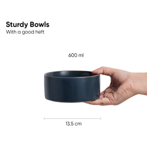 Hand holding a dark blue bowl with text and measurements on a white background
