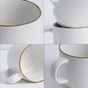 White ceramic mug with gold rim and handle on a light gray background