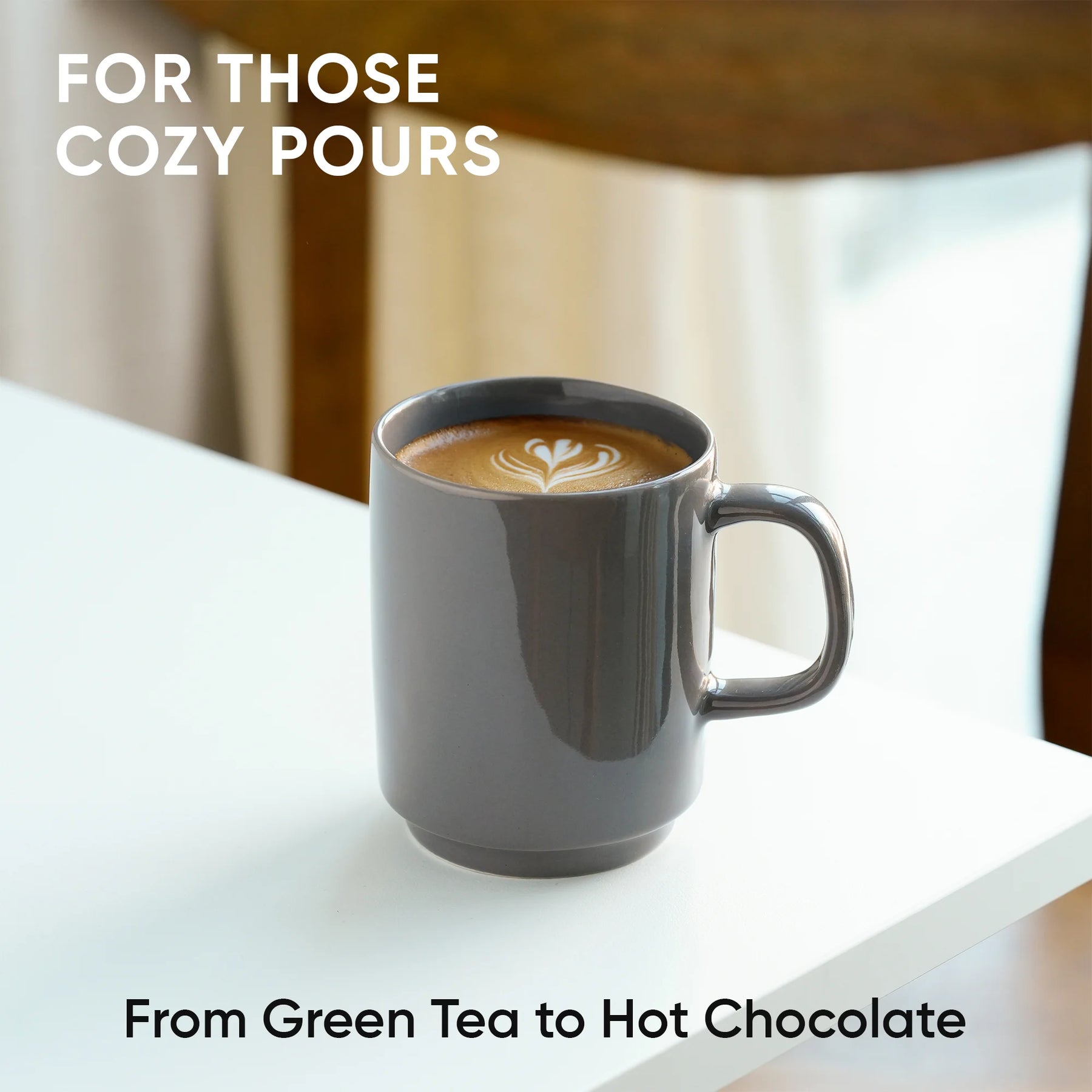 Gray mug with a heart-shaped latte art on a white surface, text 'For Those Cozy Pours' and 'From Green Tea to Hot Chocolate'.