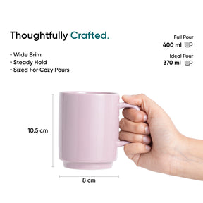 Pink mug held by a hand with measurements and text on a white background