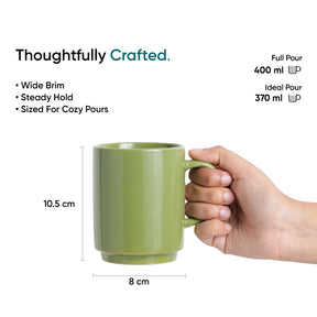Green mug held by a hand with measurements and text on a white background