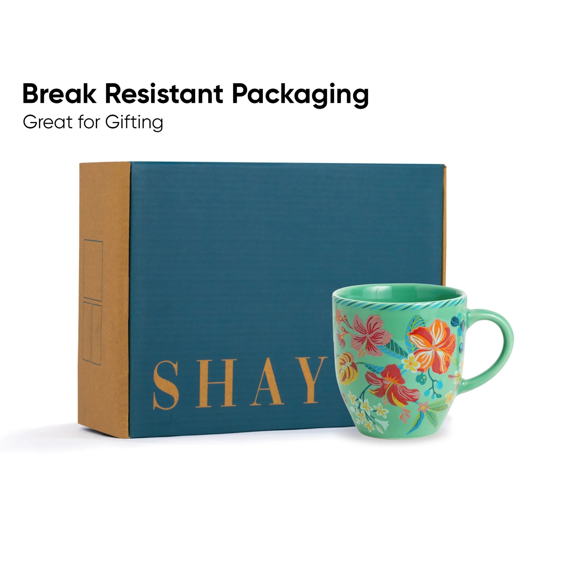 Teal mug with floral design and 'SHAY' branding in front of a blue box labeled 'SHAY'.