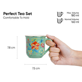 Hand holding a floral mug with measurements and volume details on a white background