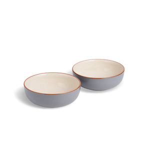 Two ceramic bowls with a gray exterior and beige interior on a white background
