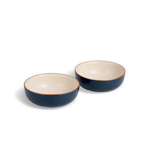 Two blue ceramic bowls with white interiors on a white background