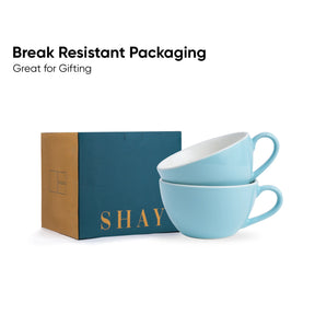 Two blue ceramic cups stacked on top of each other with a teal box labeled 'SHAY' in the background, featuring text about break-resistant packaging.