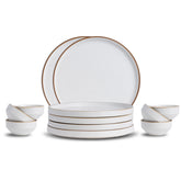 Set of white ceramic dinnerware with gold rims on a white background