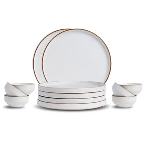 Set of white ceramic dinnerware with gold rims on a white background