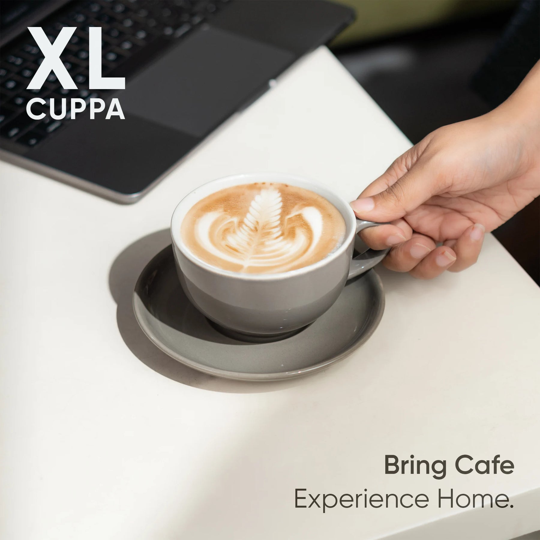 Cup of coffee with latte art on a saucer, held by a hand, with 'XL Cuppa' branding.