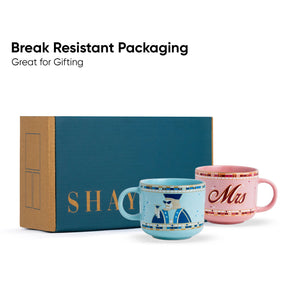 Two mugs, one blue and one pink, with 'SHAY' branding, in front of a teal box labeled 'SHAY'.