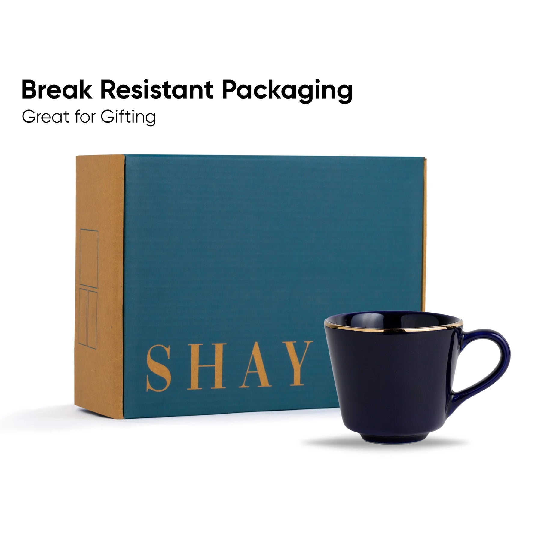 Navy blue mug with gold interior next to a teal box with 'SHAY' branding on a white background.