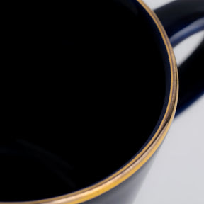 Close-up of a dark blue mug with a gold rim on a light gray background