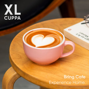 Pink mug with heart-shaped latte art on a wooden table, featuring 'XL Cuppa' branding.