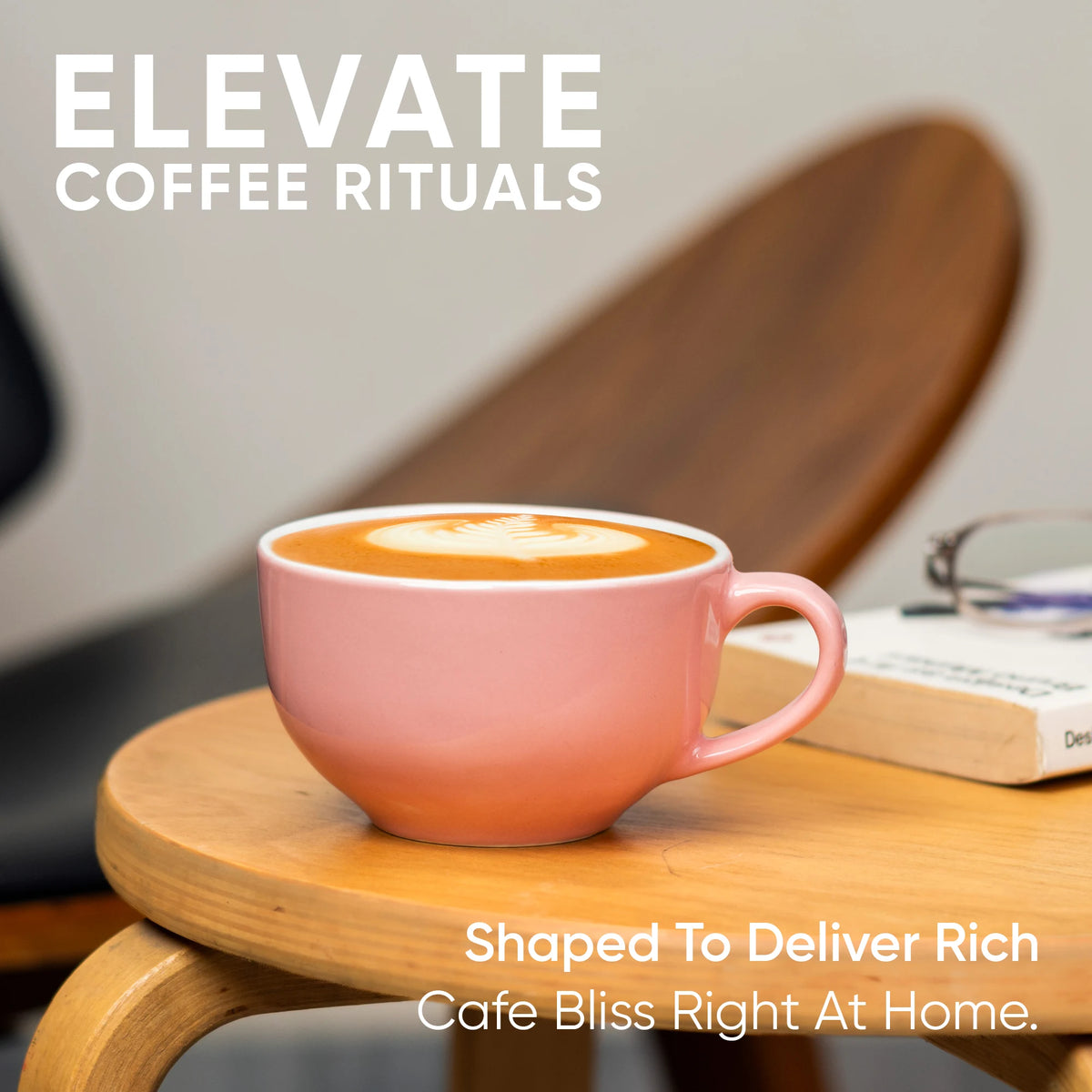 Pink coffee mug with latte on a wooden table, with text 'Elevate Coffee Rituals' and 'Shaped to deliver rich cafe bliss right at home'.