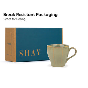 Green mug with 'SHAY' branding next to a blue and brown box on a white background.
