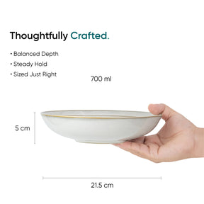 Hand holding a white bowl with dimensions and text about its features on a white background