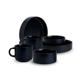 Set of black ceramic dishes including bowls and a mug on a white background