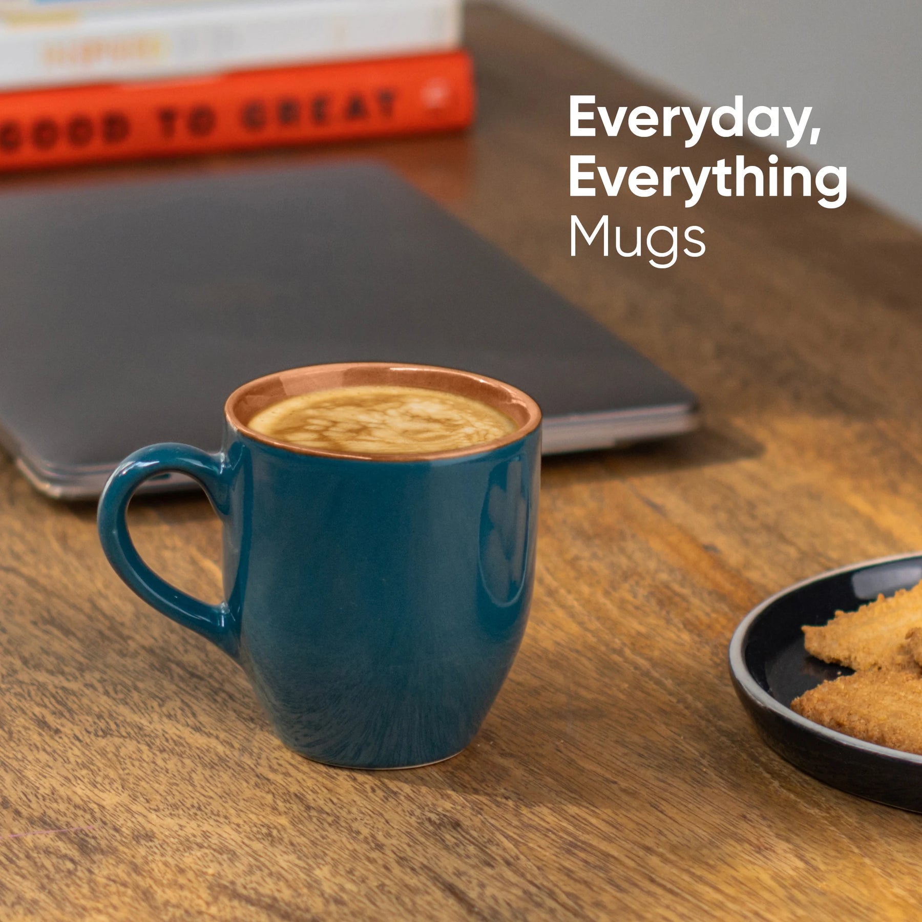 Blue mug with coffee on a wooden table with 'Everyday, Everything Mugs' text.